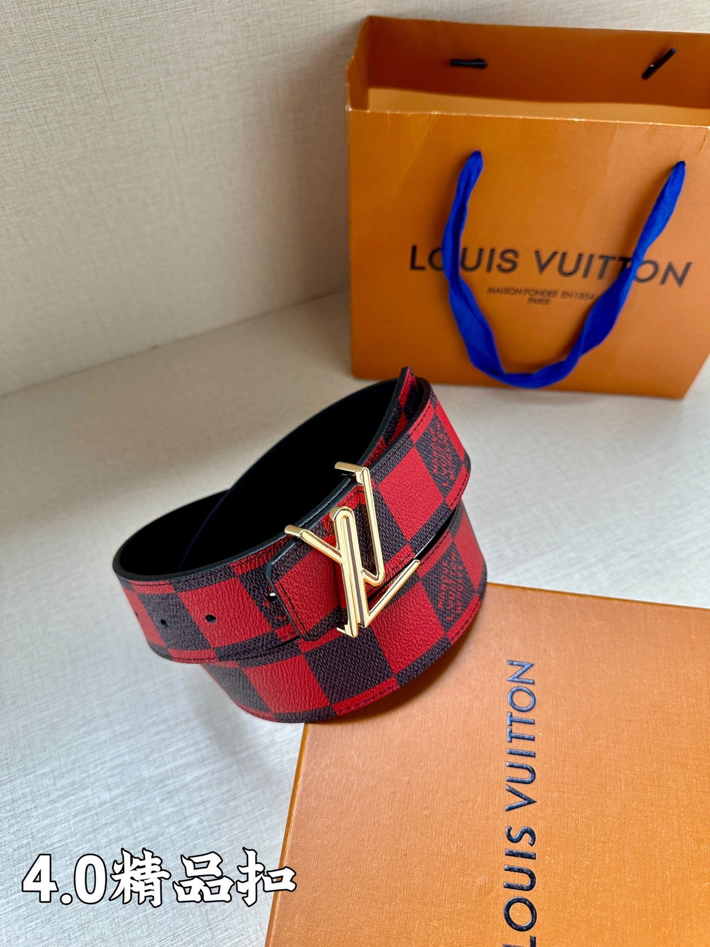 Checked fabric belt with red-and-navy pattern and gold-tone metal V buckle