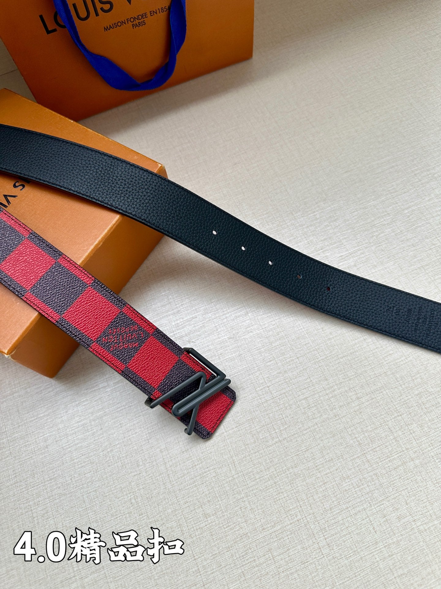 Dark blue leather belt with red/navy check strap, black buckle holes