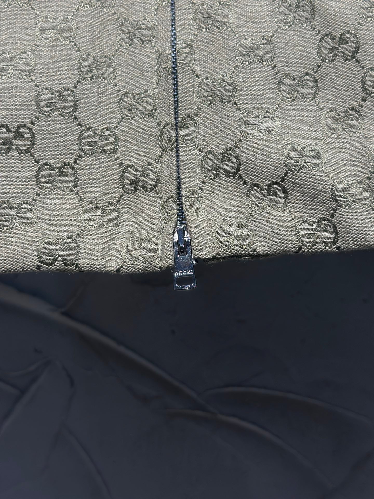 Gucci-pattern jacket zipper close-up with textured fabric