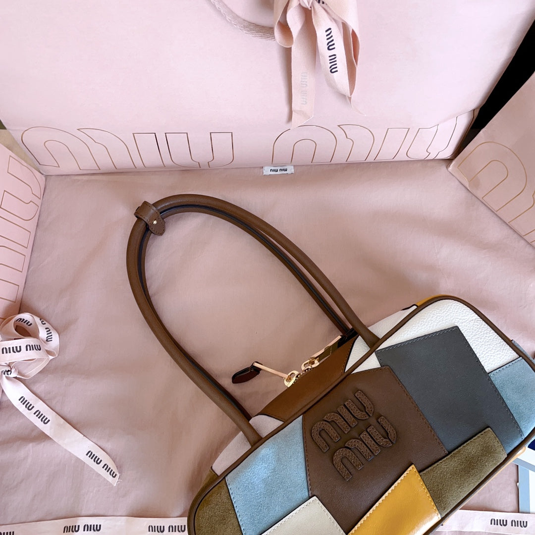 MiuMiu patchwork leather handbag close-up with top handle strap and embossed logo patch
