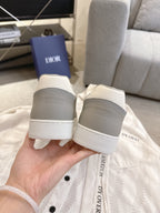 Rear view of white-and-gray Dior lace-up sneakers with branded heel tabs