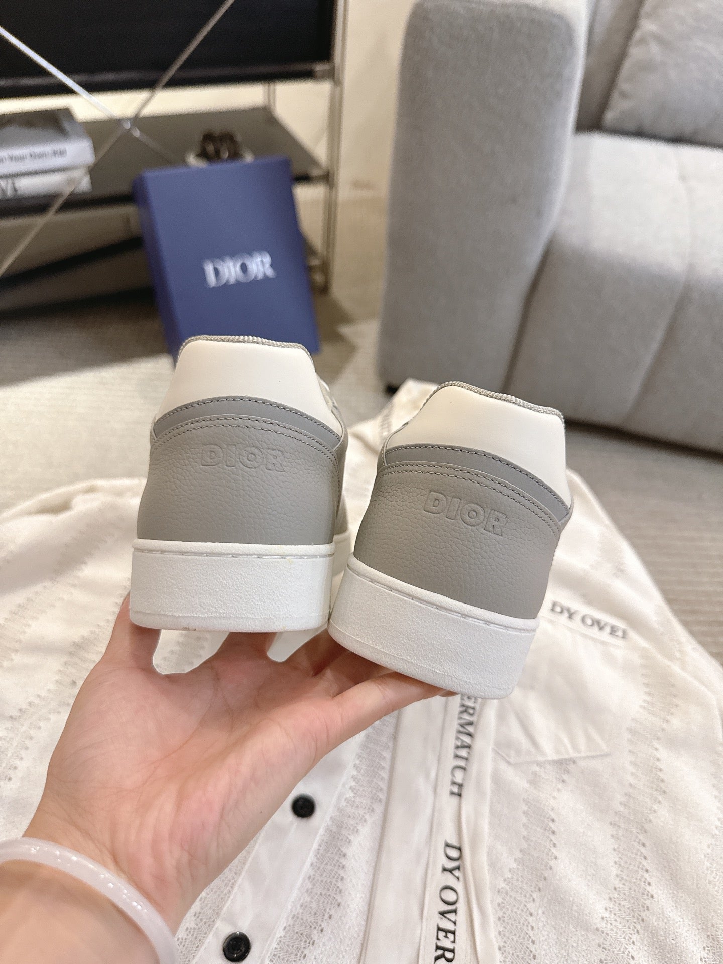 Rear view of white-and-gray Dior lace-up sneakers with branded heel tabs