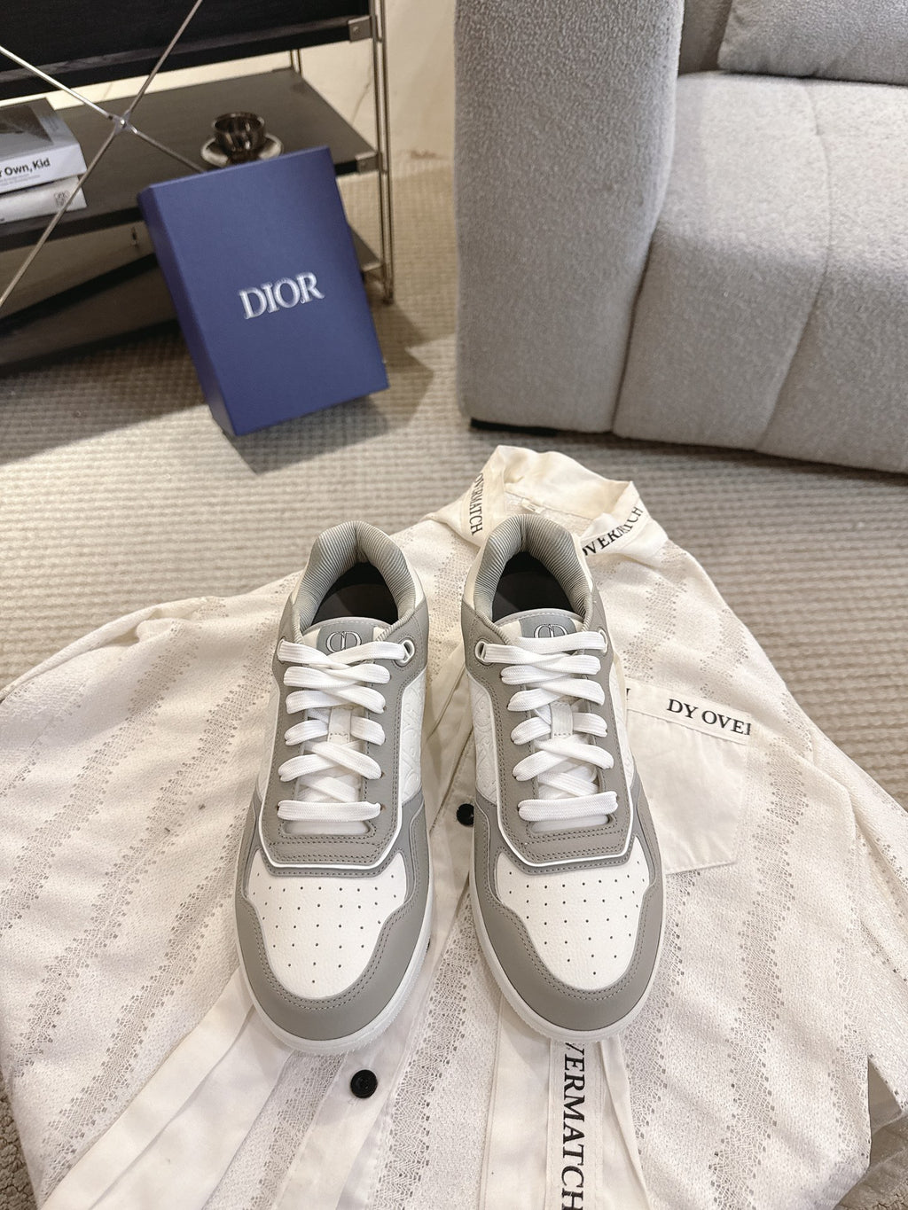 Low-top lace-up sneakers with gray and white panels, perforated toe, branding detail
