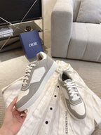 White-and-gray lace-up sneakers held in hand, side view with logo patch
