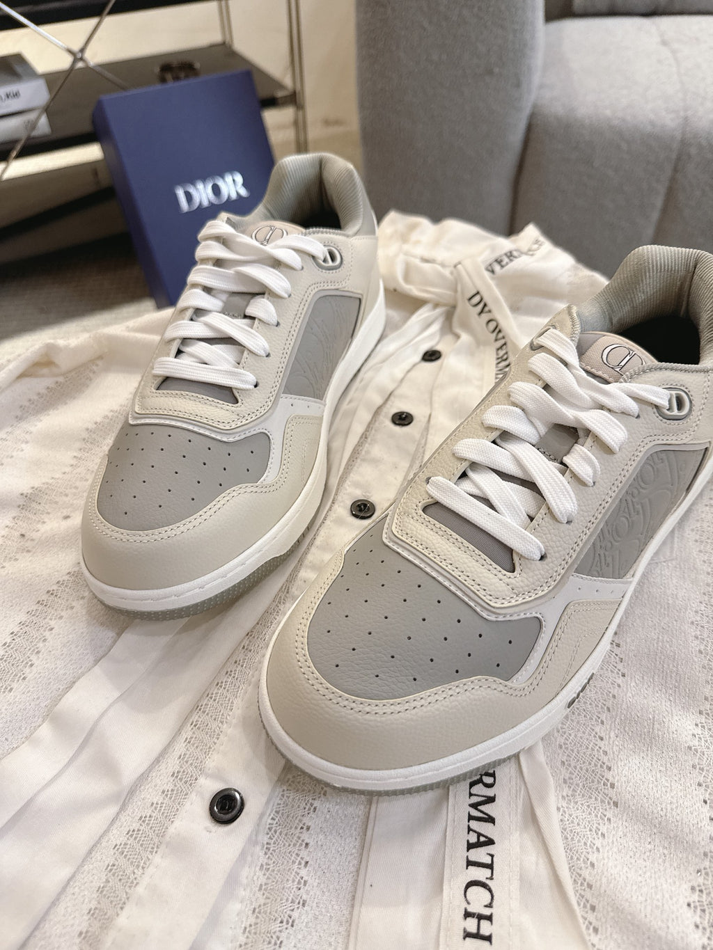 Pair of off-white low-top sneakers with gray perforated panels and white lace-ups