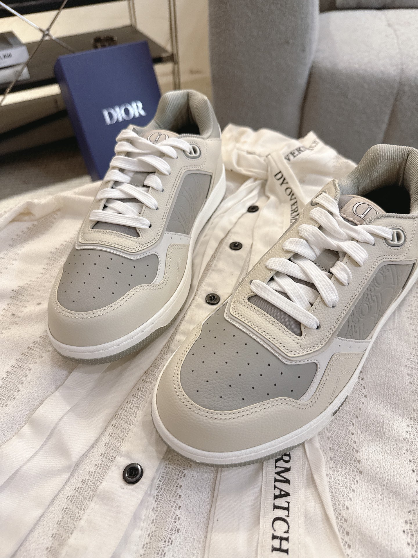 Pair of off-white low-top sneakers with gray perforated panels and white lace-ups