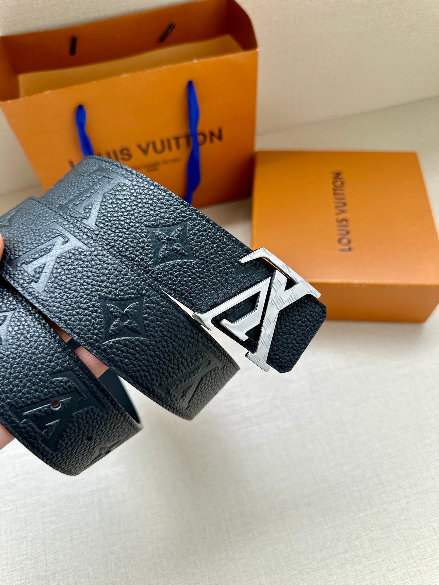 Louis Vuitton belt close-up of dark blue textured leather and silver LV buckle