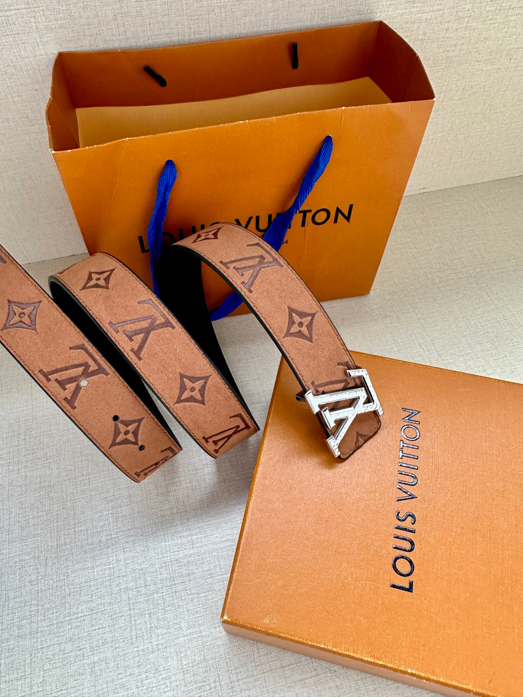 Louis Vuitton belt with monogram pattern and silver-tone LV buckle on orange box