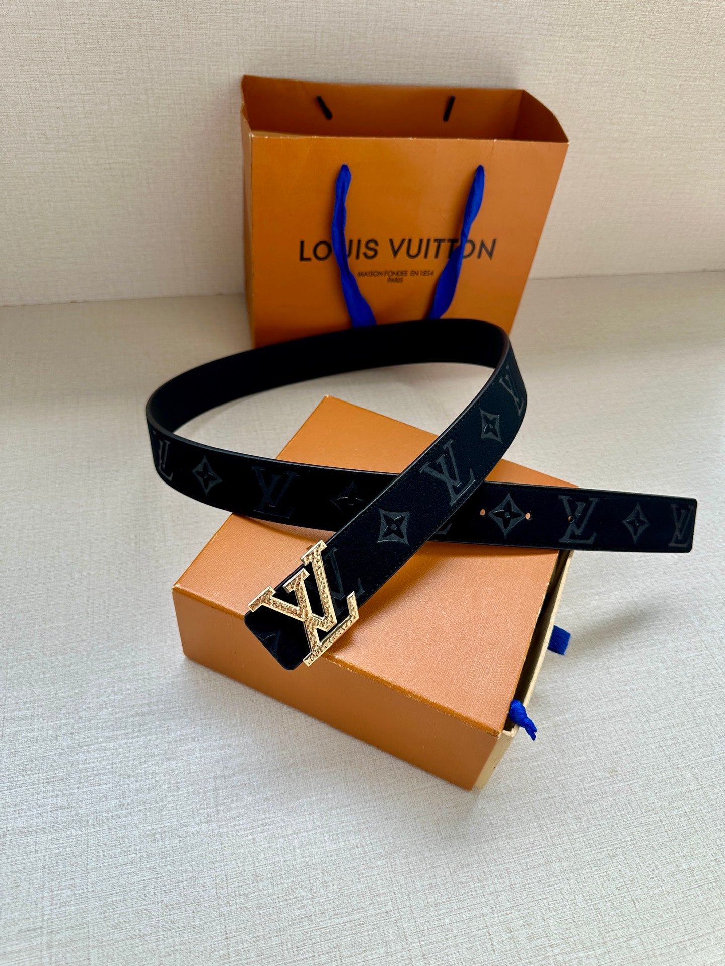 Monogram belt with dark blue strap and silver-tone buckle, looped arrangement