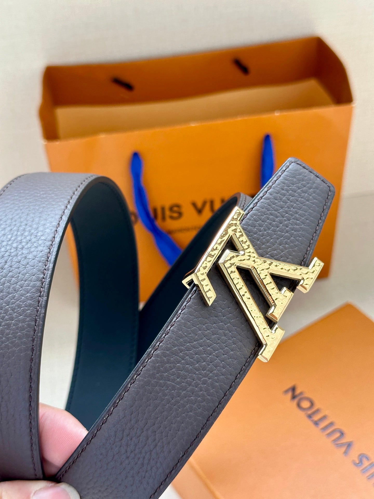 Louis Vuitton belt detail with dark leather strap and silver-tone LV logo buckle