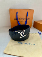 Dark blue leather belt with gold LV buckle, looped on a cloth with box behind.