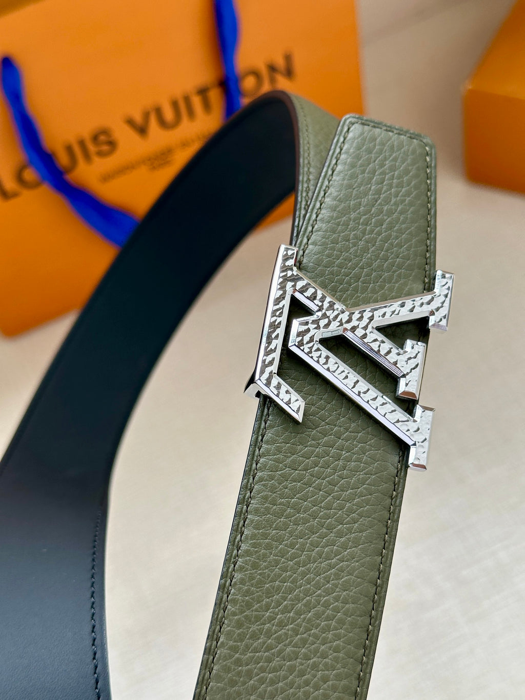 Dark green leather belt close-up with silver LV buckle