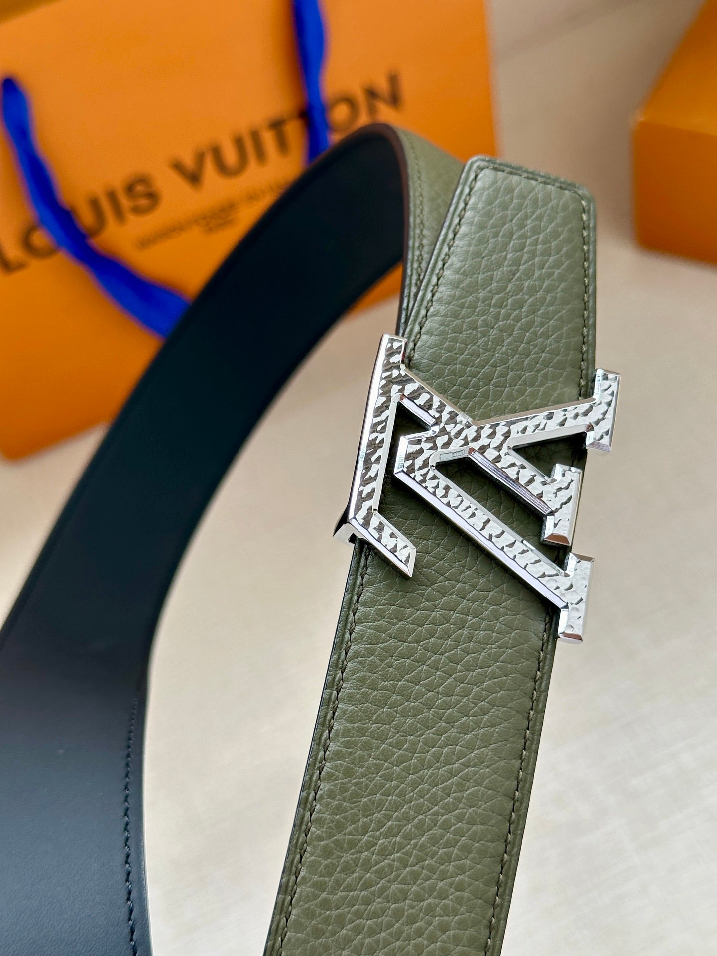 Dark green leather belt close-up with silver LV buckle