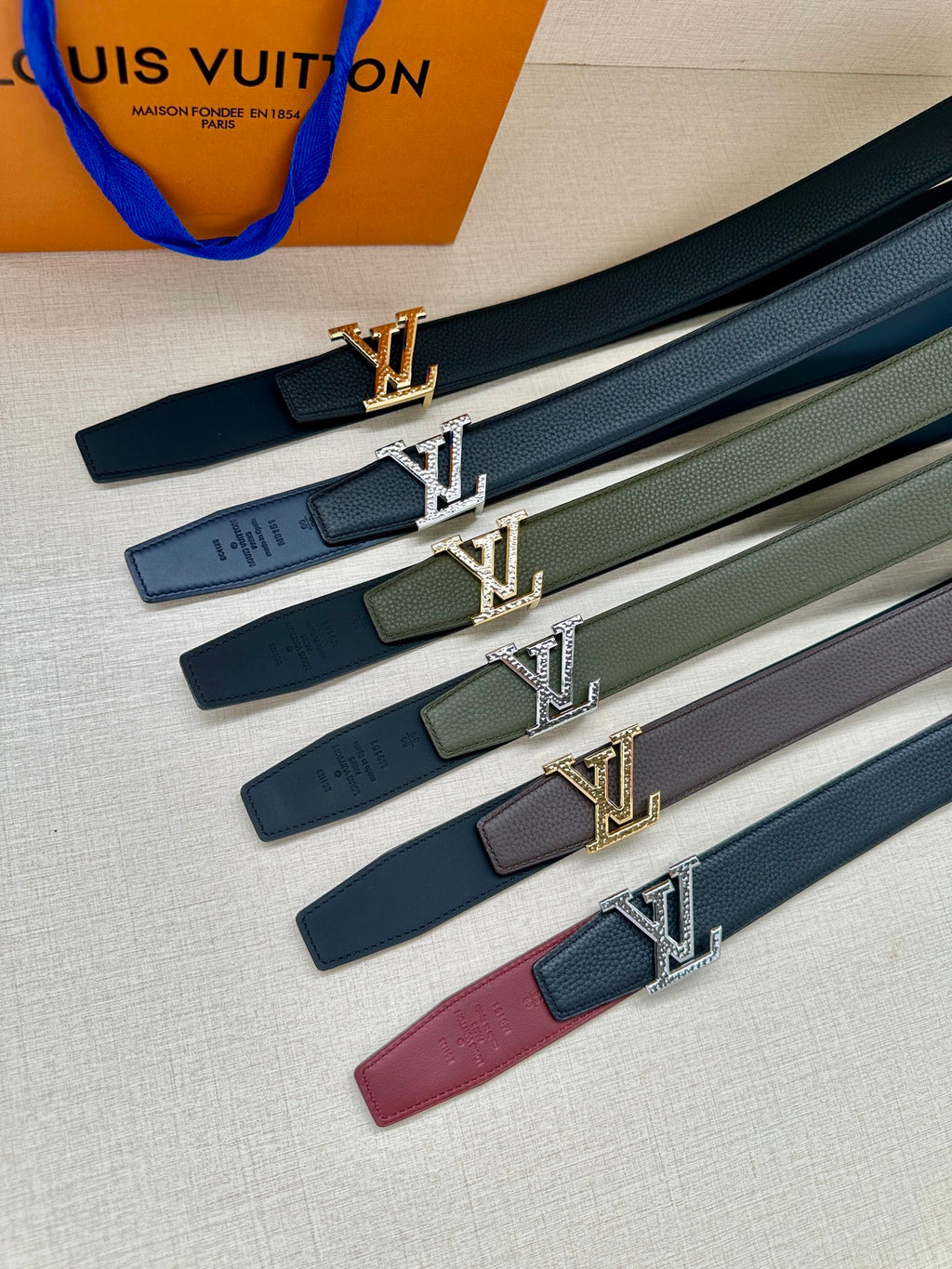 Set of leather belts in dark green, black, gray, and burgundy with silver LV buckles