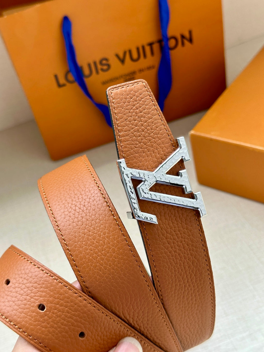 Louis Vuitton belt detail, tan leather strap with silver LV buckle