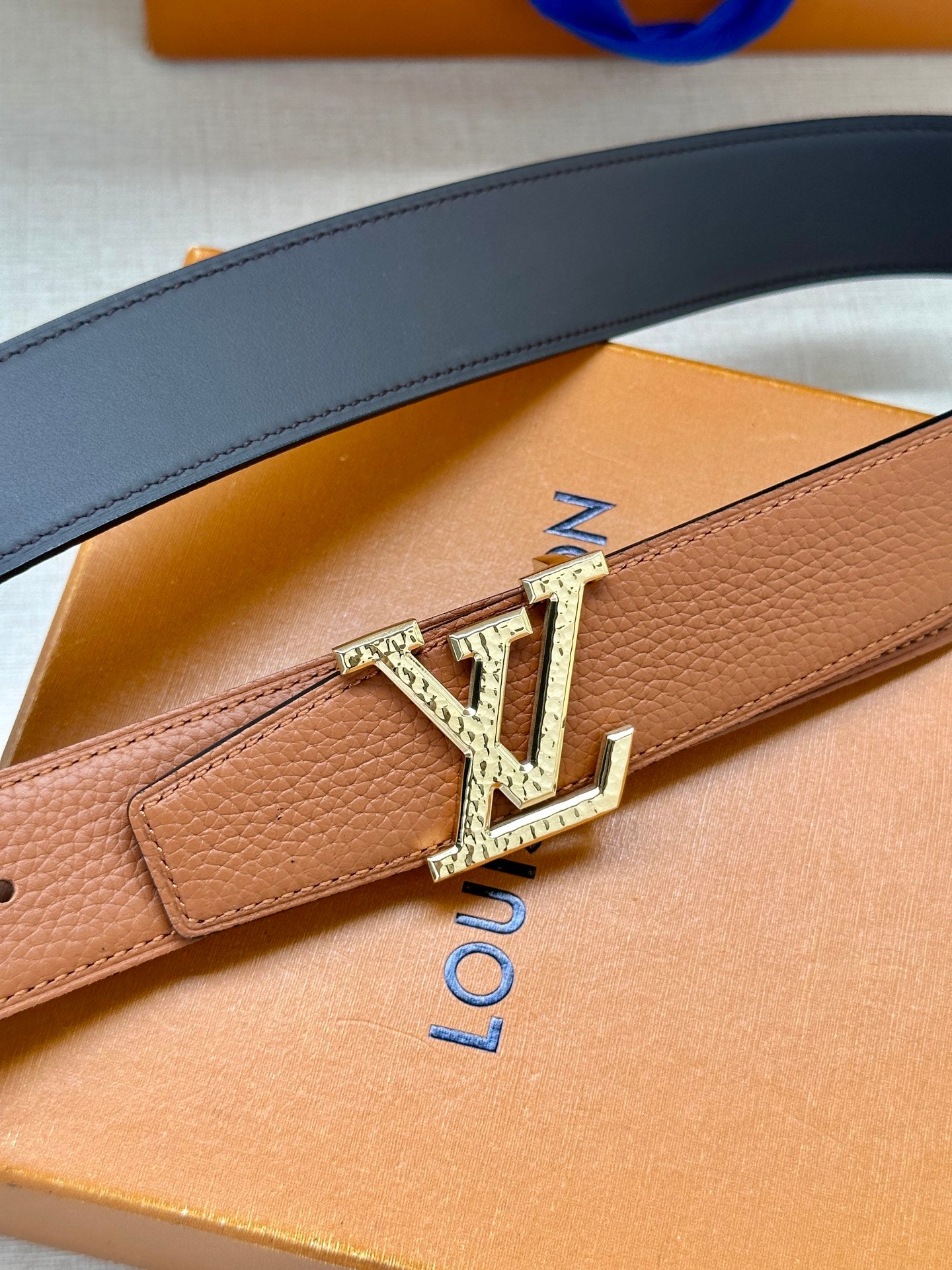 Louis Vuitton belt detail, tan leather strap with silver-toned LV buckle