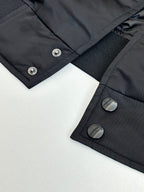 Dark navy bomber jacket close-up of snap buttons and ribbed inner cuff