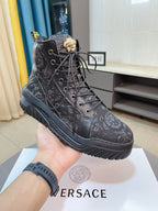 Black high-top sneakers with lace-up front, decorative emblem patch, rubber sole.