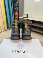 Pair of black high-top sneakers with gold emblem panels and chunky tread soles.