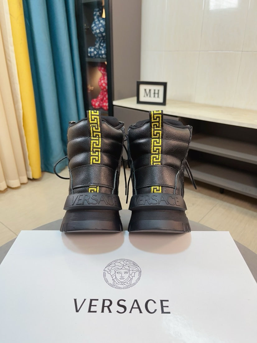 Pair of black high-top sneakers with gold emblem panels and chunky tread soles.