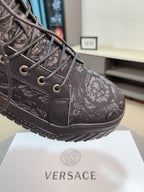 Close-up of black lace-up sneaker upper with textured logo pattern and metal eyelets.
