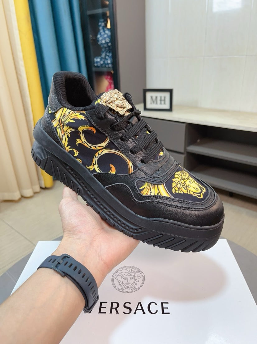 Versace platform sneaker in dark with gold baroque motif, shown in hand