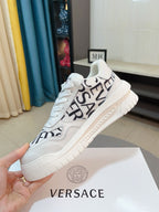 Versace white sneakers with vertical black logo text across the side