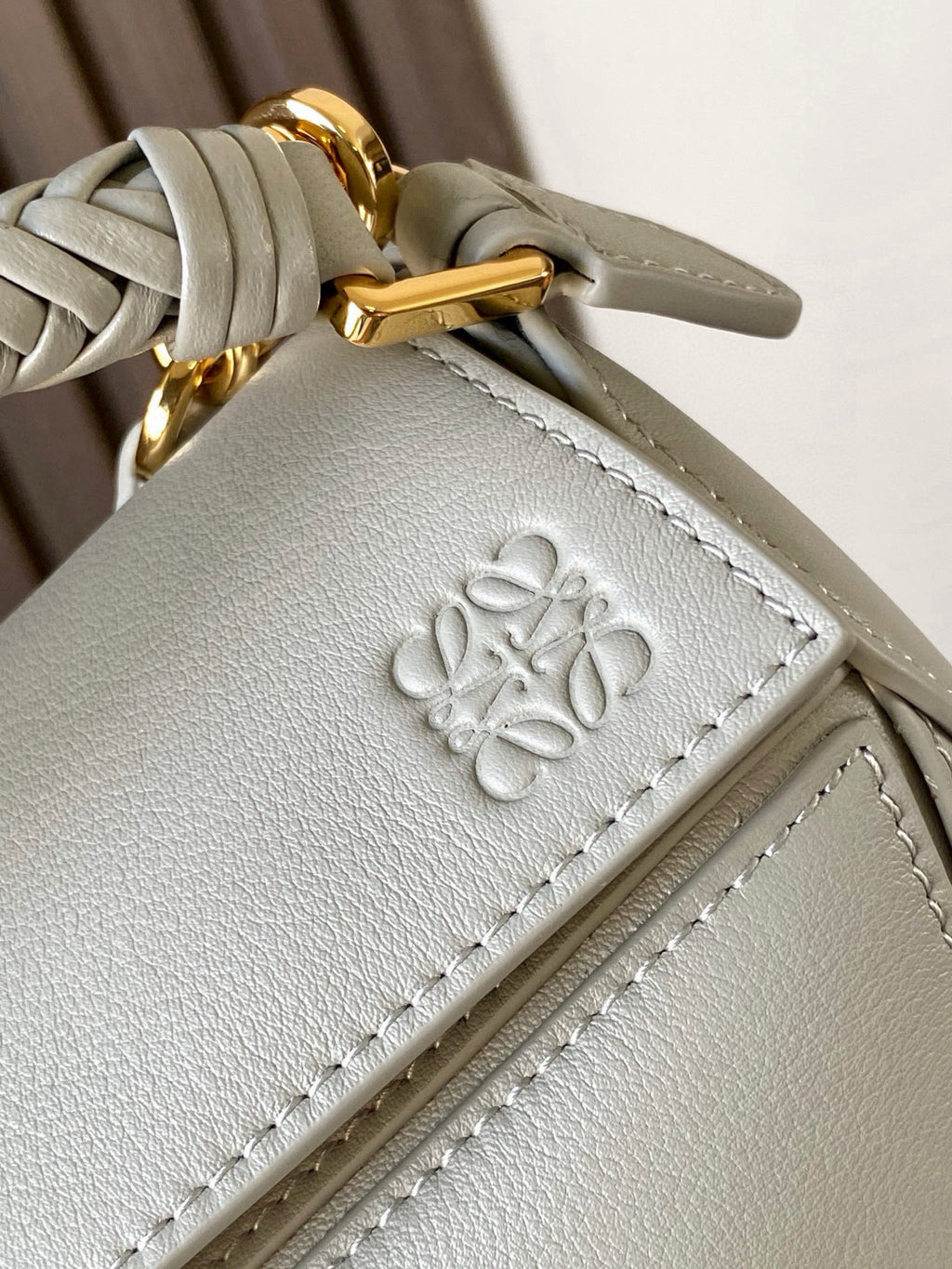 Light blue leather crossbody bag with embossed emblem and gold hardware