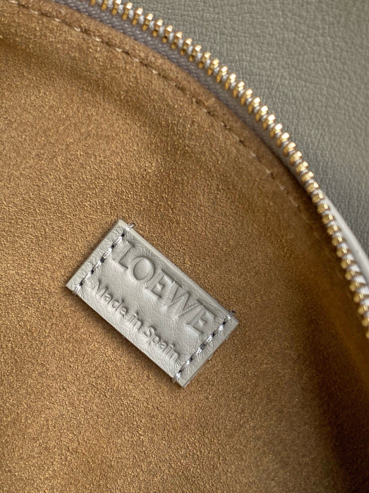 Brown suede interior tag with LOEWE lettering on light blue bag