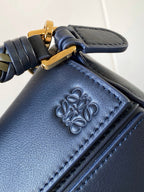 Blue leather bag corner with embossed floral logo and decorative stitching
