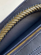 Navy leather bag zipper with gold teeth and braided trim along edge