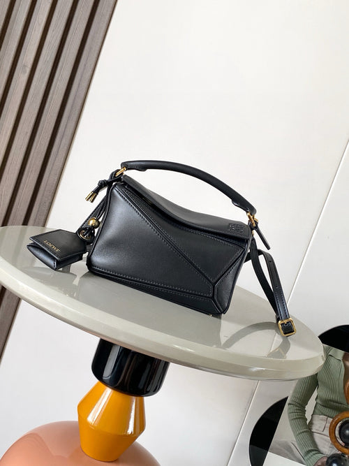 Loewe men’s black leather mini shoulder bag with curved handle, crossbody strap, gold hardware.