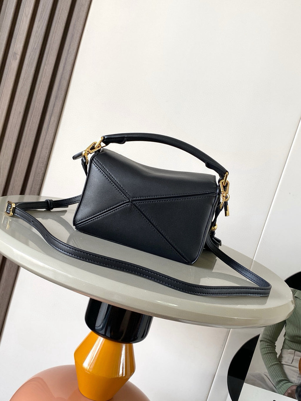 Loewe men’s black leather mini shoulder bag with curved top handle and crossbody strap, gold hardware.
