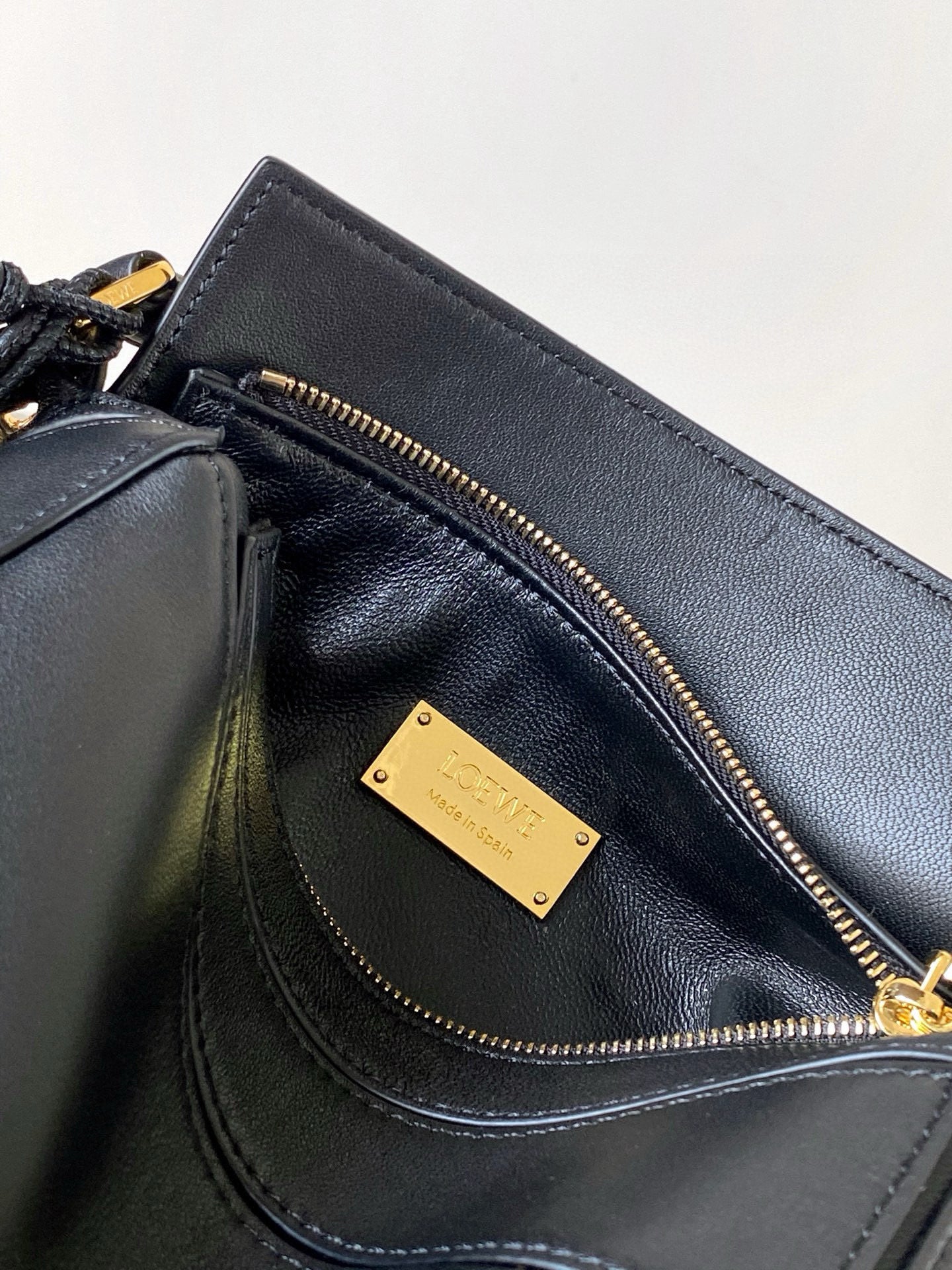 Loewe leather bag interior pocket with gold logo plaque and zip closure in dark navy