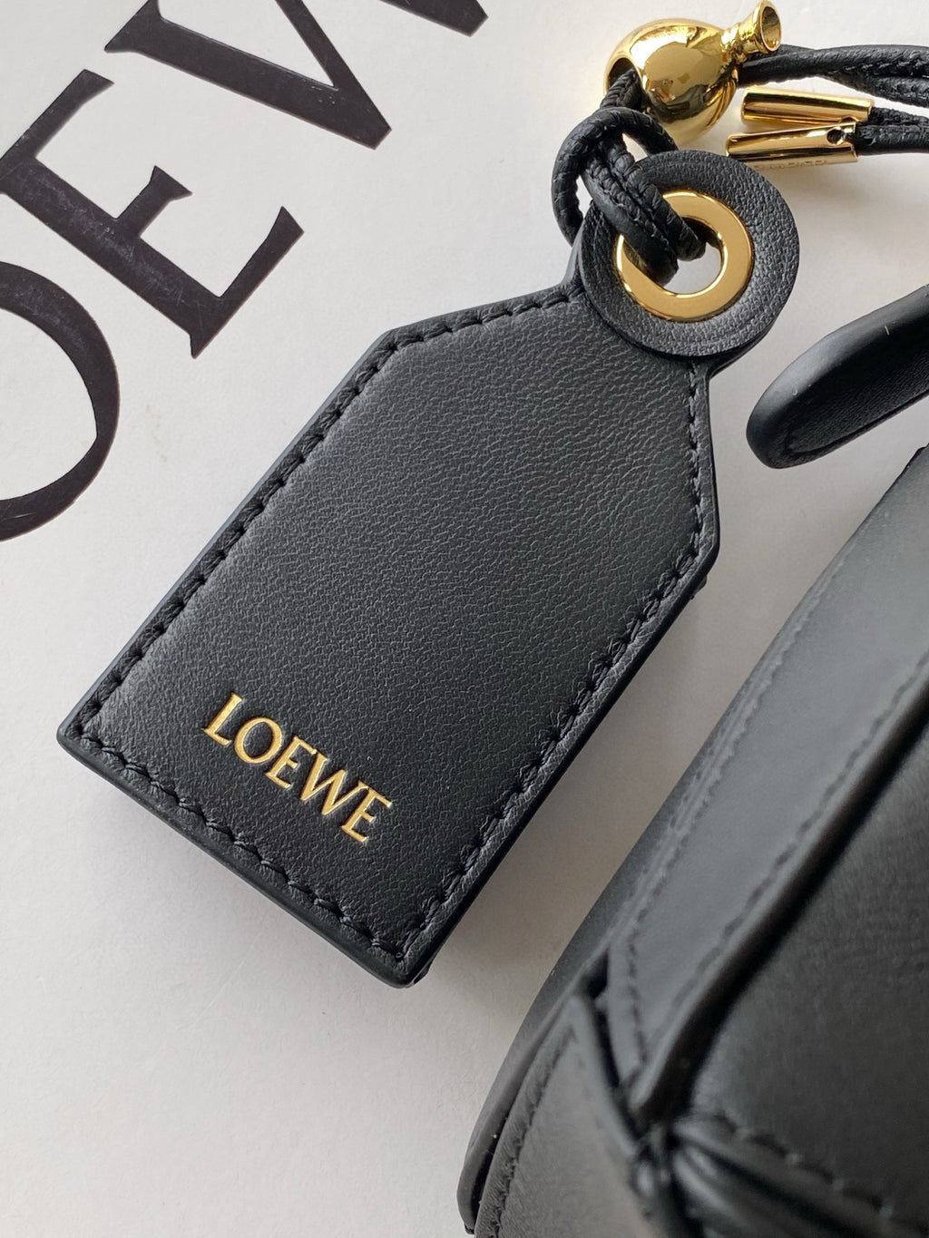 Loewe leather key holder charm in dark gray with gold “LOEWE” lettering