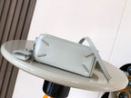 Light blue leather clutch-style bag with shoulder strap and metal accents