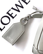 Gray leather key charm with Loewe logo, metal ring, and stitched edges