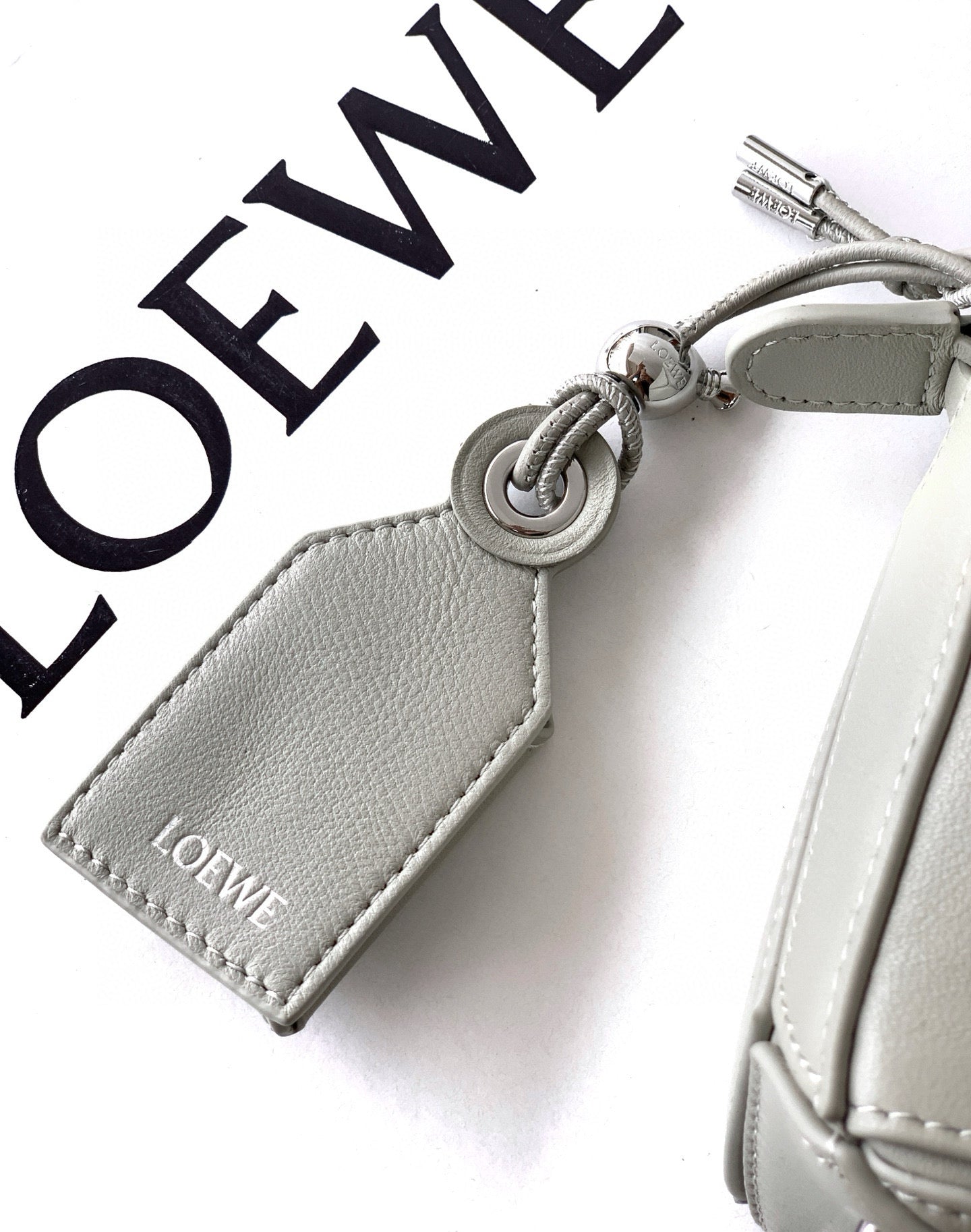 Gray leather key charm with Loewe logo, metal ring, and stitched edges