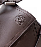 Leather bag corner with embossed LOEWE logo and stitched edge in dark taupe