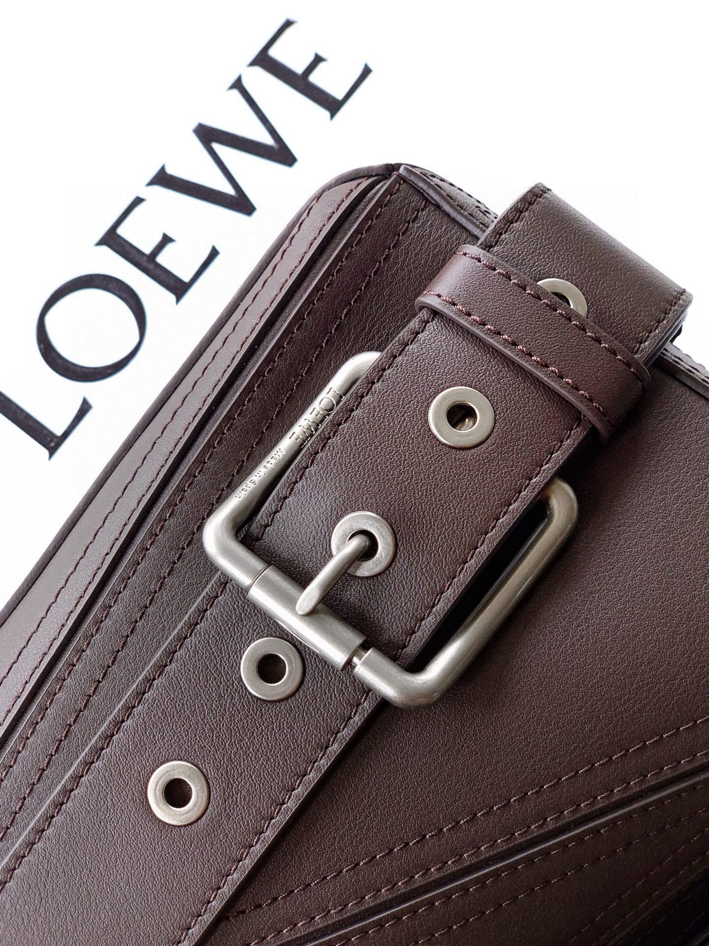 Leather bag strap keeper with silver buckle hardware and stitched edges in dark taupe