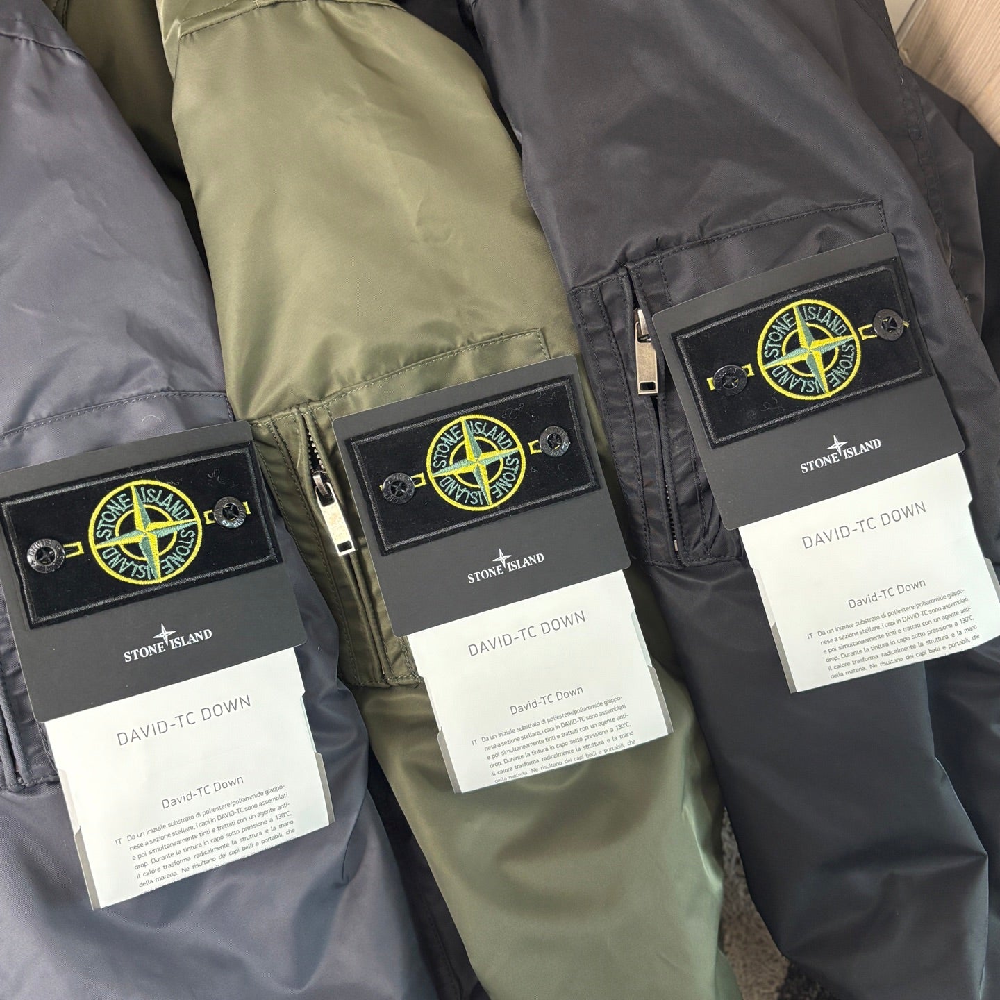 Stone Island logo patch on zip-front bomber jackets with white product tags