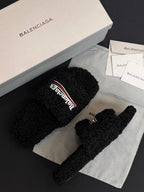 Black fuzzy slide sandals with Balenciaga logo strap, angled view