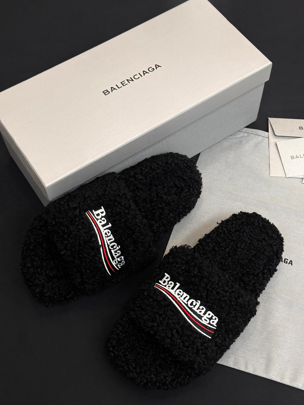 Black fuzzy slide sandals, toe straps sideways with Balenciaga logo