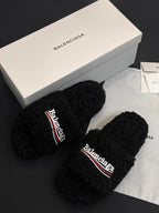 Black fuzzy slide sandals, toe straps sideways with Balenciaga logo