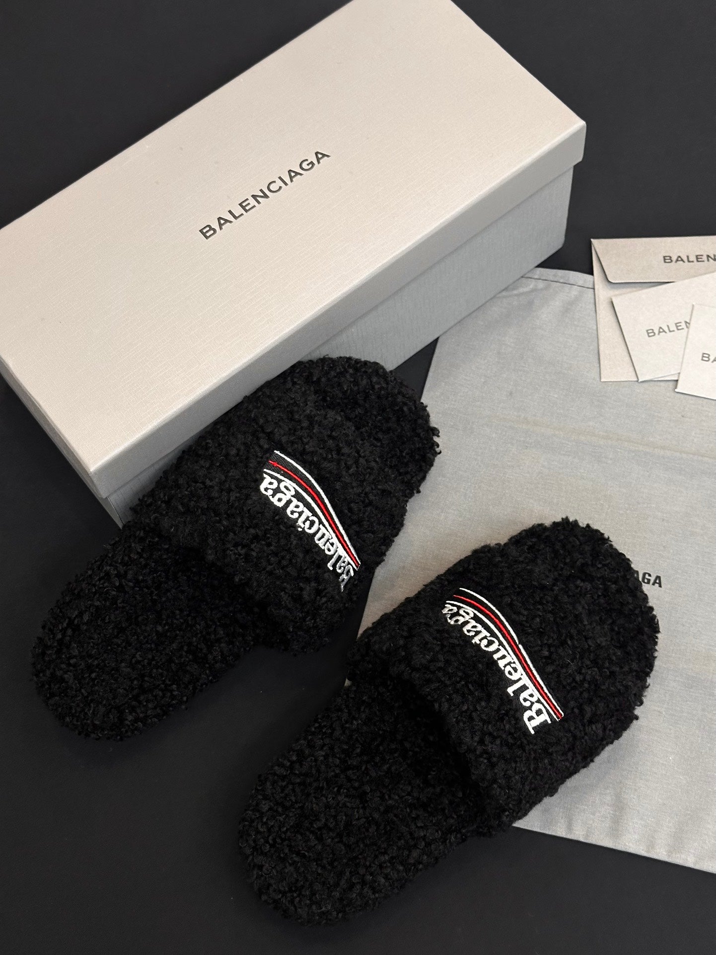 Black fuzzy slide sandals with Balenciaga logo strap, side view