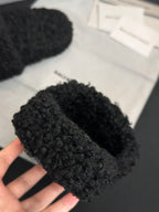 Black fuzzy slide sandal held in hand with Balenciaga logo strap
