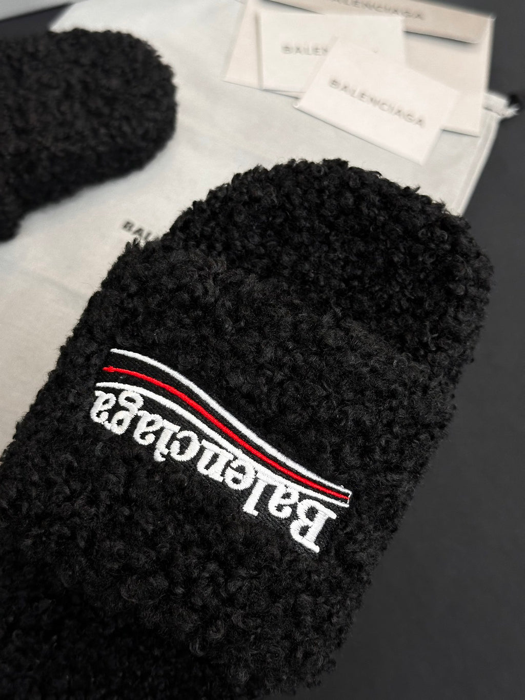 Black fuzzy sandal strap with Balenciaga logo patch and red trim