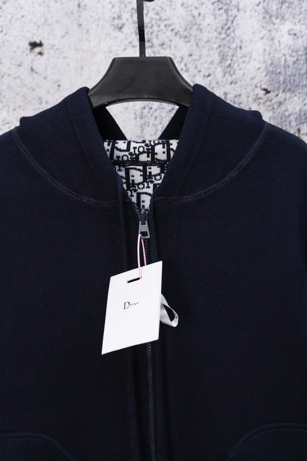 Navy zip-up hoodie close-up, hood and front zipper with Dior hang tag