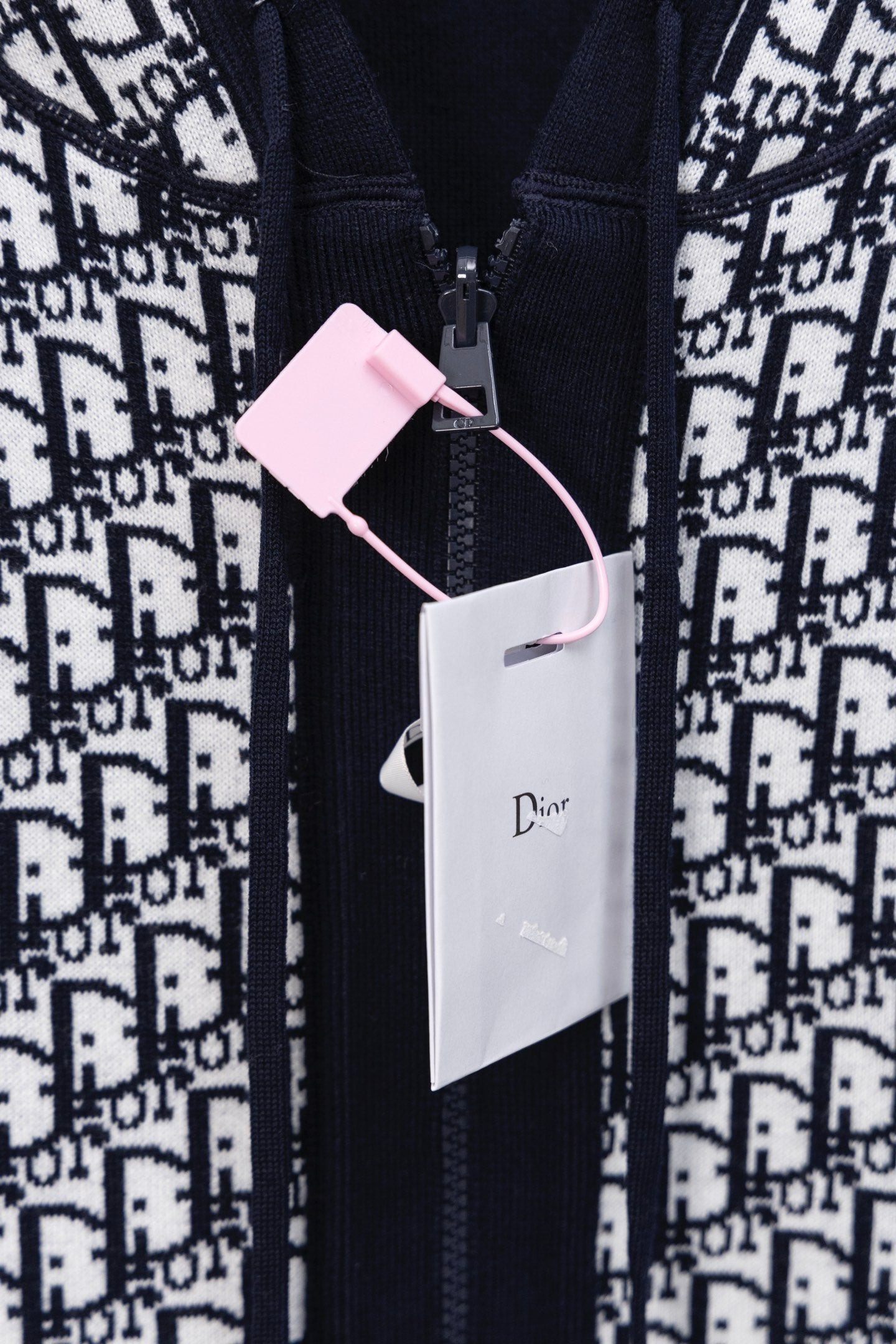 Dior hooded top with navy zipper, monogram print, and white retail tags