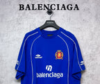 Blue short-sleeve jersey with white lines, small logo, and crest emblem